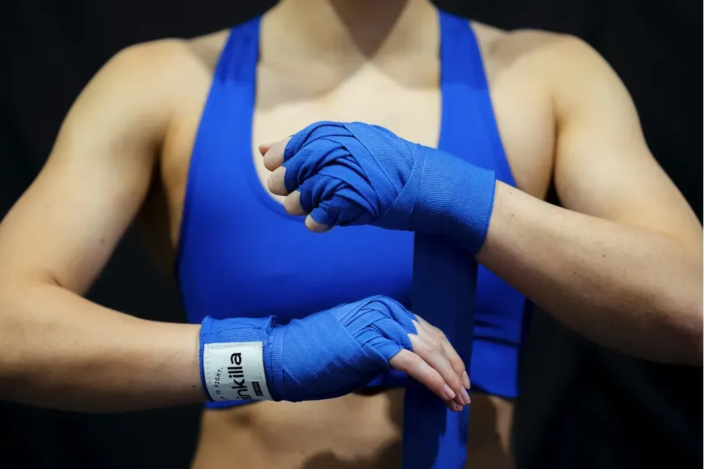Persoon wikkelt blauwe bandages om handen.